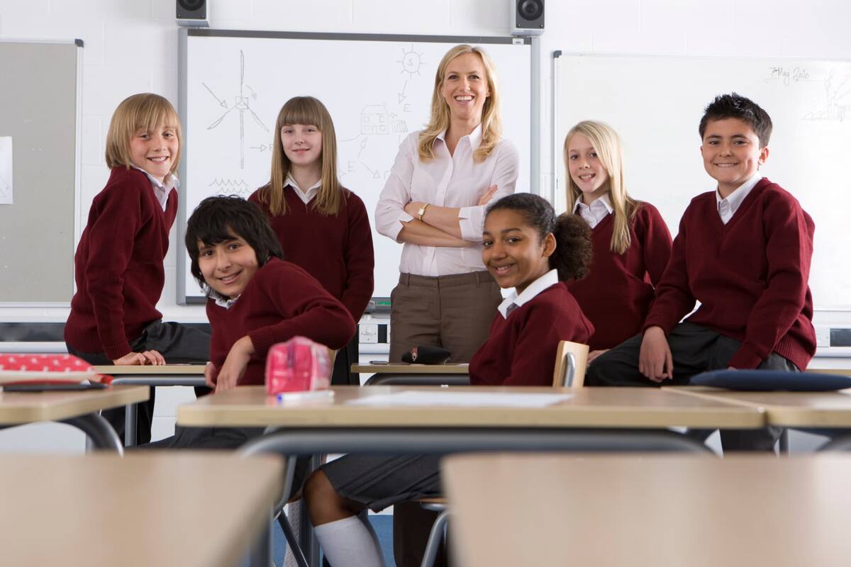 A teacher standing with a group of secondary school pupils in a classroom